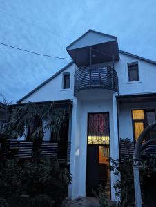 a white house with a balcony on top of it at Nino & Irodi's Guest House in Kutaisi