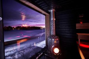 een raam met uitzicht op een besneeuwde straat in de nacht bij Luxvilla in Rovaniemi