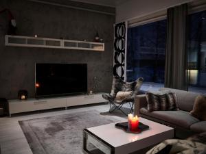 een woonkamer met een tv, een bank en een tafel bij Luxvilla in Rovaniemi