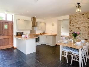 een keuken met witte kasten en een tafel en stoelen bij 2 Bed in Sidmouth 50004 in Sidbury