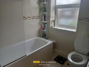 ein Bad mit einer Badewanne, einem WC und einem Fenster in der Unterkunft Goldy's place in E17 in London