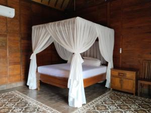 ein Schlafzimmer mit einem Himmelbett in der Unterkunft Rumah Impian Padang Kecag in Candidasa