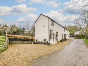 une maison blanche avec une clôture à côté d'un chemin de terre dans l'établissement 3 Bed in Barnstaple 60511, à Swimbridge