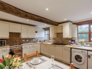 una cocina con armarios blancos y una mesa con flores en 3 Bed in Barnstaple 60511, en Swimbridge