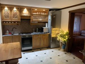 a kitchen with wooden cabinets and a stainless steel refrigerator at Садиба VAKO in Verkhniy Bystryy