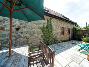 eine Terrasse mit zwei Bänken und einem Sonnenschirm in der Unterkunft 2 bed property in Godshill Isle of Wight IC149 in Godshill