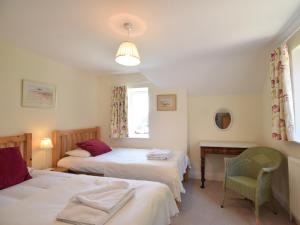 1 dormitorio con 2 camas, silla y ventana en 5 Bed in Corfe Castle DC061, en Corfe Castle
