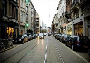 a car driving down a street with parked cars at Charming National Street Room in the Heart of Antwerp in Antwerp +2 photos