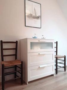 Vestidor blanco con silla y una foto en la pared en Ker Eon - Les Gîtes de la Côte d'Amour, en Batz-sur-Mer