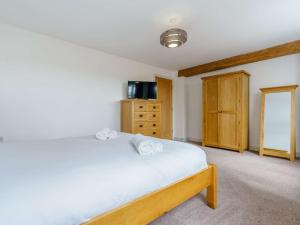 a bedroom with a white bed and a wooden cabinet at 3 Bed in Malton 75899 in Amotherby