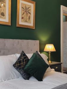 a green bedroom with a bed with pillows and a lamp at Beautiful Georgian New Town 2 bed apartment in Edinburgh