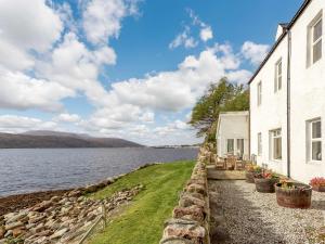 a house next to a body of water at 6 Bed in Ullapool CA259 in Ullapool