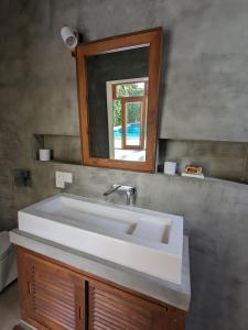 een badkamer met een witte wastafel en een spiegel bij LoSu Polhena in Polhena