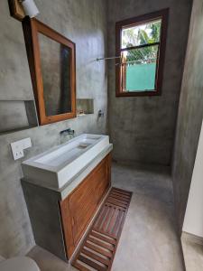 een badkamer met een wastafel, een spiegel en een raam bij LoSu Polhena in Polhena