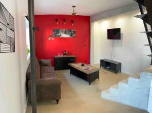 sala de estar con sofá y pared roja en Les Gîtes Warenne - 2, en Saint-Étienne-au-Mont