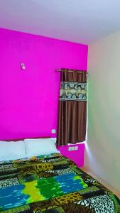 a bedroom with a pink wall and a bed at Holiday home in Ooty