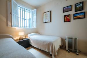 sypialnia z dwoma łóżkami i oknem w obiekcie APARTAMENTO EN CASA PALACIO CON PISCINA 15 MAYO a 15 OCTUBRE w Sewilli