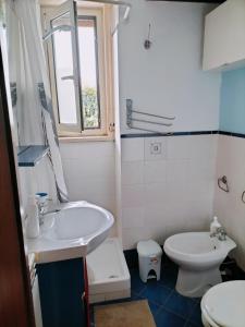 La salle de bains blanche est pourvue d'un lavabo et de toilettes. dans l'établissement Apartment Ro a Mondello, à Mondello