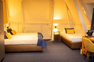 2 camas en una habitación con paredes amarillas en Hotel de Gulden Leeuw, en Workum