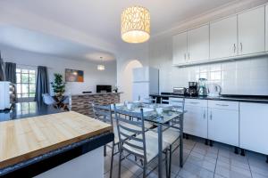 a kitchen with white cabinets and a table and chairs at Blue Lee Residence in Aljezur