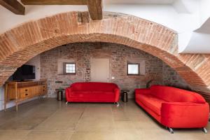 salon z 2 czerwonymi krzesłami i ceglaną ścianą w obiekcie numa I Felice Rooms & Apartments we Florencji