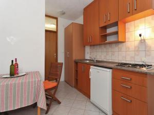 a kitchen with wooden cabinets and a table with a bottle of wine at Apartments Lampion in Vir