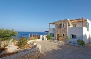 een huis met een stenen muur naast de oceaan bij Villa Avgi in Agios Nikolaos