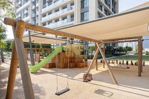 a playground with a green slide and swings at Luxurious 3BR Apartment Amazing view of Burj Khalifa in Dubai