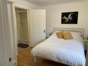 1 dormitorio con cama blanca y ducha en Modern The Mews Apartment en Bury Saint Edmunds