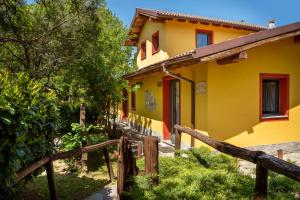 uma casa amarela com uma cerca em frente em Il Fiorile em Borghetto Di Borbera