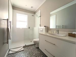 a bathroom with a sink and a toilet and a mirror at Beachy Head Hideaway 11 Seaside Luxury Stay in Plettenberg Bay +19 photos