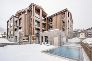 an apartment building with a swimming pool in the snow at Summit Seefeld in Seefeld in Tirol