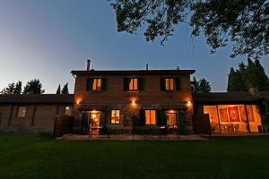 a large brick house at night with lights on at Agriturismo Podere il Leccio in Castiglione della Pescaia