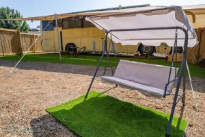 a swing bed with a canopy in a yard at MashikaBus משיקה בס אירוח מפנק על גלגלים in Ta‘oz