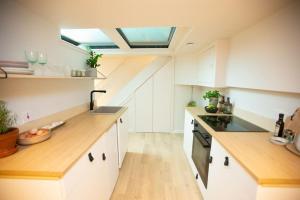 a kitchen with white cabinets and a skylight at Chorlton Stylish Studio & Roof Terrace Apartments in Manchester