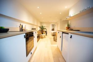 a kitchen with white cabinets and a living room at Chorlton Stylish Studio & Roof Terrace Apartments in Manchester