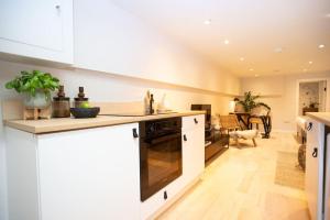 cocina con armarios blancos y encimera en Chorlton Stylish Studio & Roof Terrace Apartments, en Mánchester