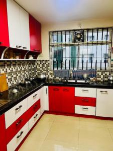 a kitchen with red and white cabinets and a window at Ak22 stays Bardhaman Burdwan in Barddhamān