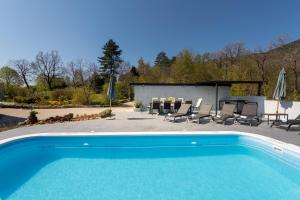 a swimming pool with chairs and a table and umbrellas at Villa Tulipa by Briskva in Mošćenice