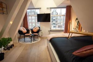 a bedroom with two chairs and a bed and windows at Best Neighbourhood Apartment in Amsterdam