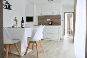 a kitchen with white cabinets and a white table and chairs at Rezort pod Roháčmi in Vitanová