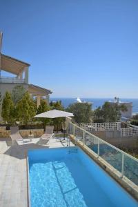 a blue swimming pool with an umbrella and chairs and an umbrella at Summer Villa , Kaki Thalassa in Dhaskalión