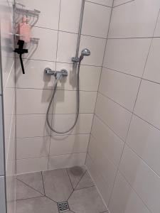 a shower with a hose in a white tiled bathroom at Allee zum See in Schüttorf