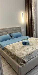a bedroom with a bed with blue sheets and blue pillows at Красивая квартира ЖК Алматым in Almaty