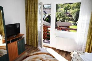 a room with a large window and a television at Casa Ștefănuț in Moieciu de Sus