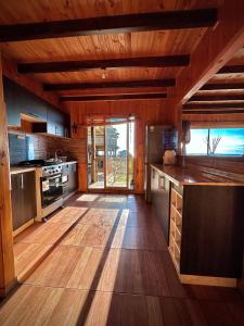 a large kitchen with wooden floors and a large window at Cabaña en chovellen in Pelluhue