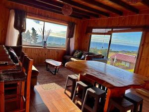 een woonkamer met een houten tafel en een groot raam bij Cabaña en chovellen in Pelluhue