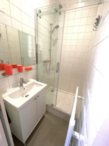 La salle de bains est pourvue d'un lavabo et d'une douche avec une porte en verre. dans l'établissement Capitole, Grand T1 bis, lumineux, neuf., à Toulouse