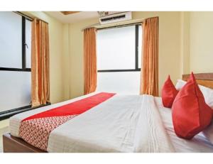 um quarto com uma cama grande e almofadas vermelhas em Hotel Om Shanti Palace, Kolkata em Calcutá