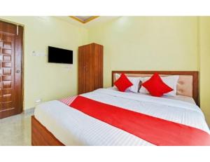 um quarto com uma cama grande e almofadas vermelhas em Hotel Om Shanti Palace, Kolkata em Calcutá